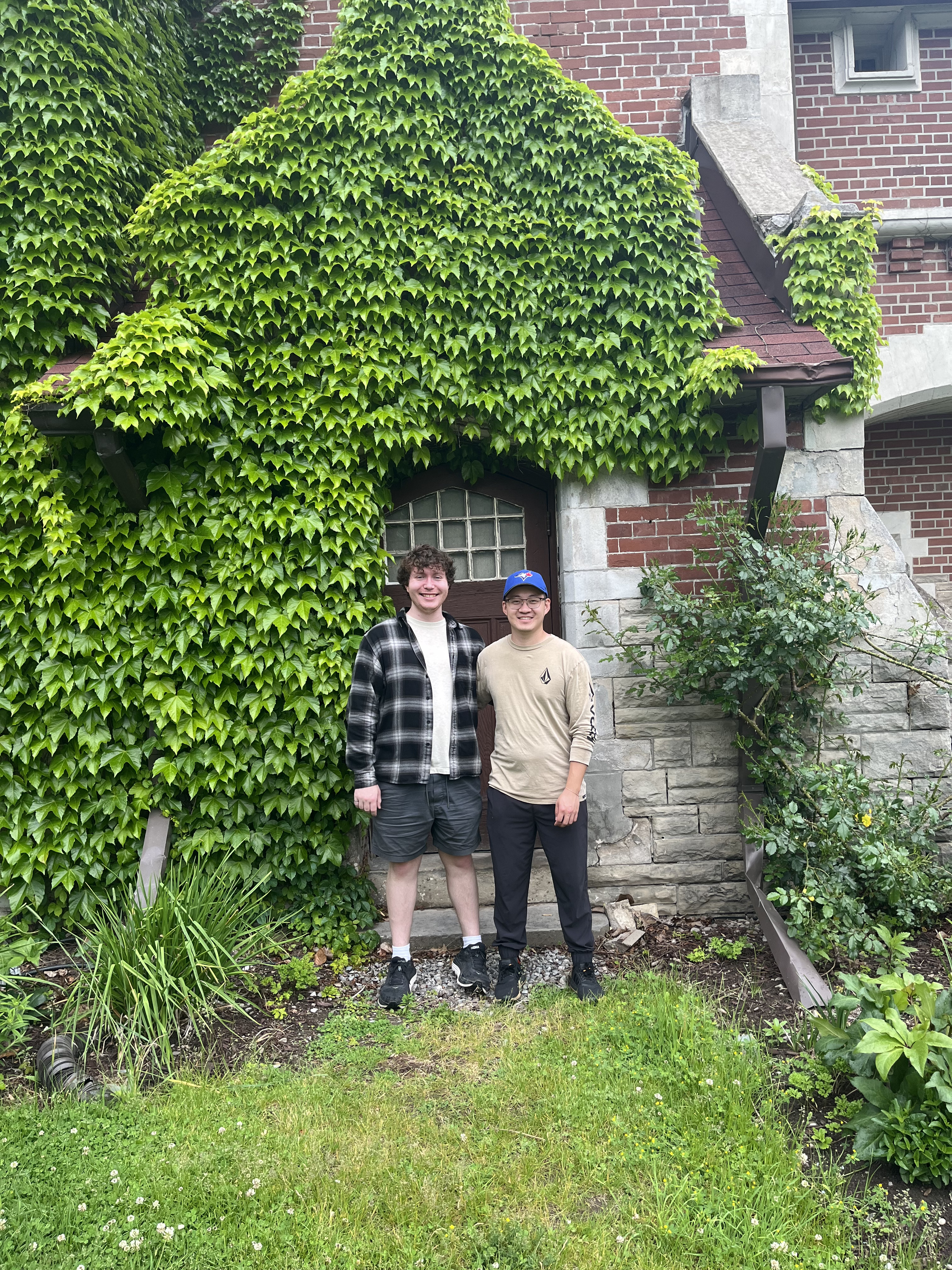 Image of Alex and Aric in front of a leafy house.